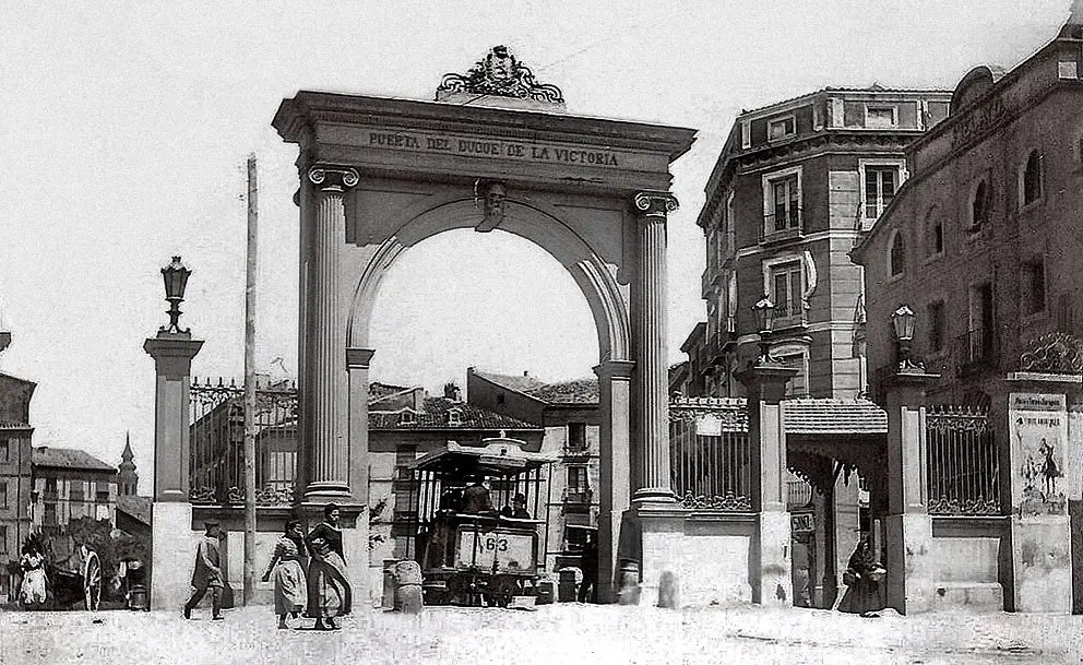 La Puerta del Duque de la Victoria en hierro colado, con el tranvía de mulas atravesando el arco central